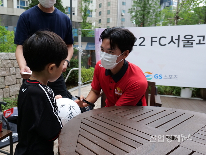 FC서울 소속 임민혁 선수가 축구교실에 참여한 아이에게 싸인볼을 선물하고 있다. 사진=GS건설