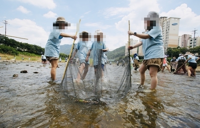 참가자들이 멸종위기 천연기념물 황쏘가리의 치어를 방류하고 있다(사진=환경재단 제공)